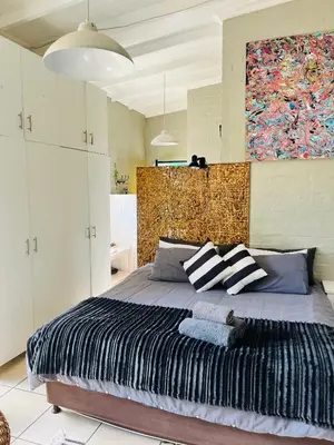 a bedroom with a large bed with a painting on the wall at Lemontree in Hermanus