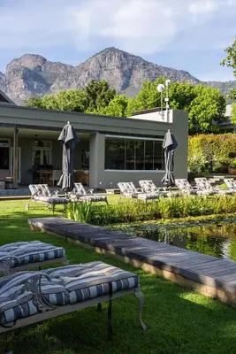a resort with chairs and a pool and mountains in the background at Angala in Simondium