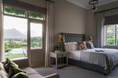 a bedroom with a bed and a couch and windows at Cape Vue Country House in Franschhoek