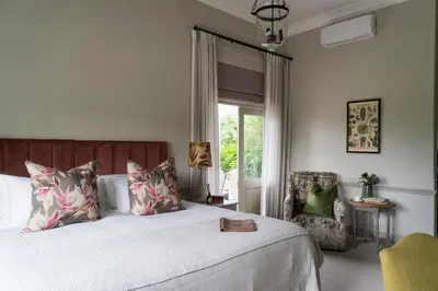 a bedroom with a large bed and a chair at Cape Vue Country House in Franschhoek