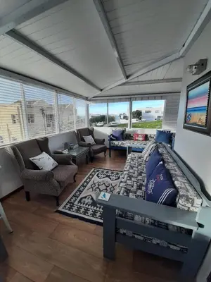 a living room with a couch and chairs and windows at Siesta in Hermanus
