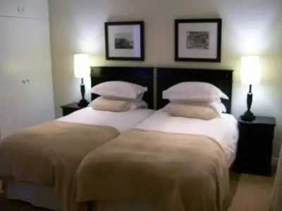 two beds in a hotel room with two lamps at Pelagus Guest House in Hermanus