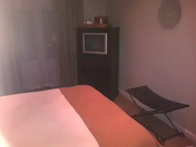 a bedroom with a bed and a chair in it at Nautilus Guest House in Hermanus