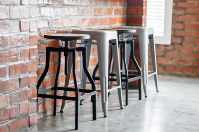 a row of stools in front of a brick wall at Rustic Retreat Apartment in Durbanville in Durbanville