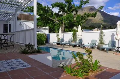 a patio with a pool and chairs and a fence at Chapter House Boutique Hotel by The Living Journey Collection in Franschhoek