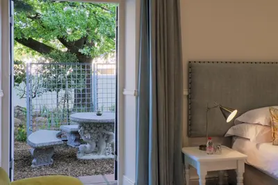 a room with a door open to a patio with a table at Chapter House Boutique Hotel by The Living Journey Collection in Franschhoek