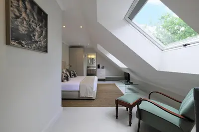 a attic bedroom with a bed and a window at Chapter House Boutique Hotel by The Living Journey Collection in Franschhoek
