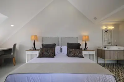 a bedroom with a large bed and a desk at Chapter House Boutique Hotel by The Living Journey Collection in Franschhoek