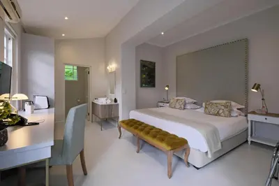 a bedroom with a large white bed and a desk and a bed sidx sidx sidx at Chapter House Boutique Hotel by The Living Journey Collection in Franschhoek