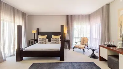 a bedroom with a bed and a chair and windows at Atlantic Waves Guest House in Cape Town