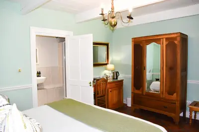 a bedroom with a bed and a sink and a mirror at Knorhoek Country Guesthouse in Stellenbosch