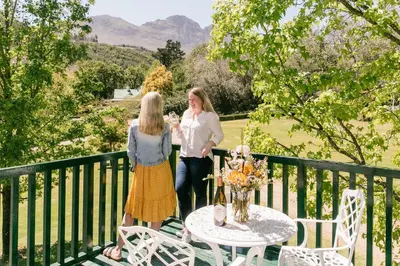 two women standing on a balcony with a table at Knorhoek Country Guesthouse in Stellenbosch