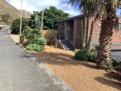 a brick house with a palm tree next to a street at Studio with unforgettable View in Gordonʼs Bay