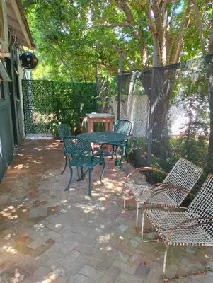 a patio with a table and chairs and a fence at Feet Up Cottage in Somerset West