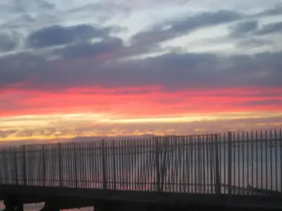 a sunset over a bridge over a body of water at Nagua bay in Gordonʼs Bay