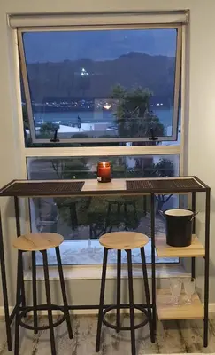 a table and two stools in front of a window at Nagua bay in Gordonʼs Bay