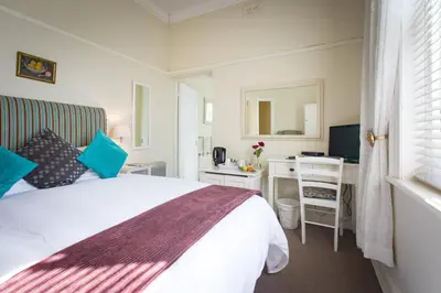 a bedroom with a bed and a desk and a mirror at Brooklands House in Cape Town