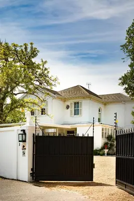 a white house with a black gate at Brooklands House in Cape Town