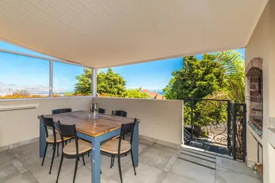 a dining room with a table and chairs and a large window at Irene Avenue Apartment with sea views in Somerset West