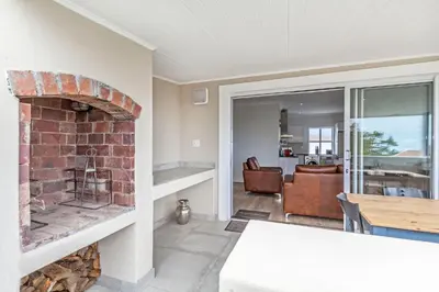 a living room with a brick fireplace and a dining room at Irene Avenue Apartment with sea views in Somerset West