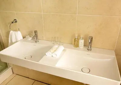 a white bathroom sink with two glasses and towels at Hotel du Vin Franschhoek in Franschhoek