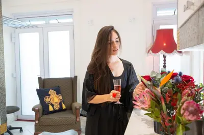 a woman holding a glass of wine in a room with flowers at Adrian D'Cap Boutique Manor in Stellenbosch