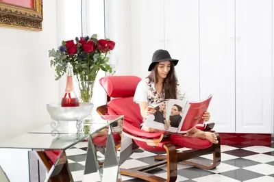 a woman sitting in a red chair reading a magazine at Adrian D'Cap Boutique Manor in Stellenbosch