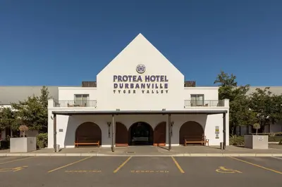 a white building with a sign on the side of it at Protea Hotel by Marriott Cape Town Durbanville in Bellville