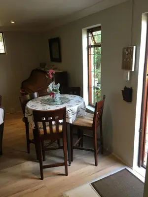 a dining room with a table and chairs and a room with a window at Geranium Studio in Somerset West