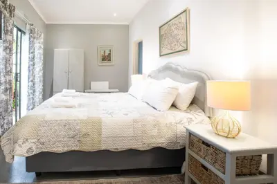 a bedroom with a bed and a lamp on a table at Rouana Guest Farm in Stellenbosch