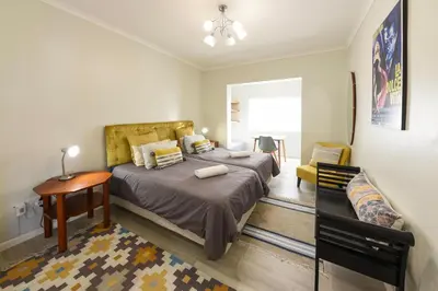 a bedroom with a bed and a table and a chair at Die Badhuis, for Fabulous living! Sleeps 4, Private pool in Gordonʼs Bay