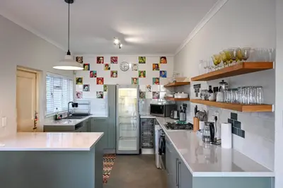 a large kitchen with white counters and a refrigerator at Die Badhuis, for Fabulous living! Sleeps 4, Private pool in Gordonʼs Bay