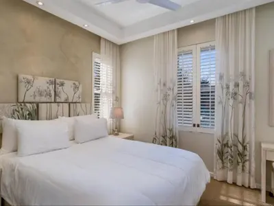 a white bedroom with a large white bed and windows at Glen Abbey Apartments On The Erinvale Golf And Country Estate in Somerset West