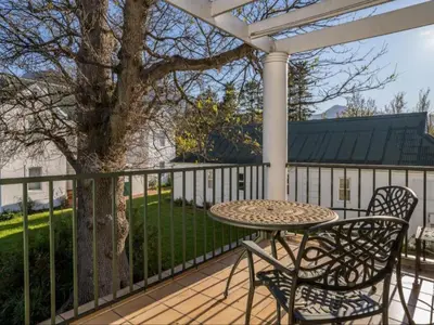 a table and chairs on a deck with a pergola at Glen Abbey Apartments On The Erinvale Golf And Country Estate in Somerset West