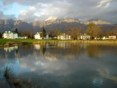 a large lake with houses and mountains in the background at Glen Abbey Apartments On The Erinvale Golf And Country Estate in Somerset West