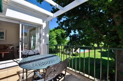 a patio with a table and chairs on a porch at Glen Abbey Apartments On The Erinvale Golf And Country Estate in Somerset West