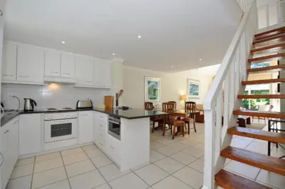 a kitchen with white cabinets and a dining room at Glen Abbey Apartments On The Erinvale Golf And Country Estate in Somerset West
