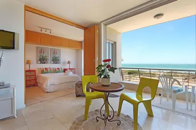 a bedroom with a bed and a table and chairs at Neptune Isle 214 in Cape Town