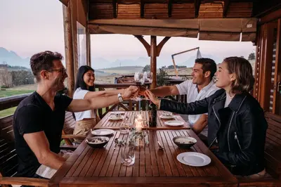 a group of people sitting around a table drinking wine at The Log Collective in Stellenbosch