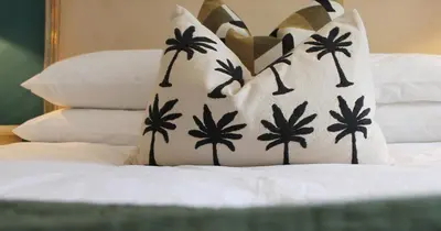 a bed with a pillow with palm trees on it at Mount Grace Country House in Greyton