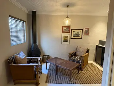 a living room with chairs and a table and a stove at Mount Grace Country House in Greyton