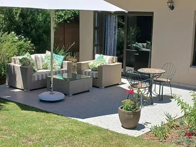 a patio with couches and a table and an umbrella at Cottage@Somerset in Somerset West
