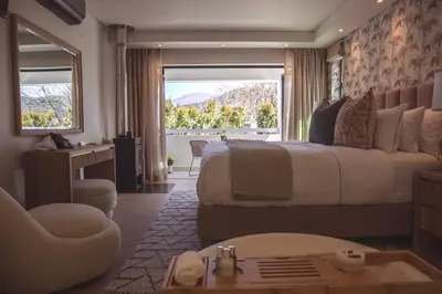 a bedroom with a large bed and a large window at Le Petit Manoir Boutique Hotel in Franschhoek