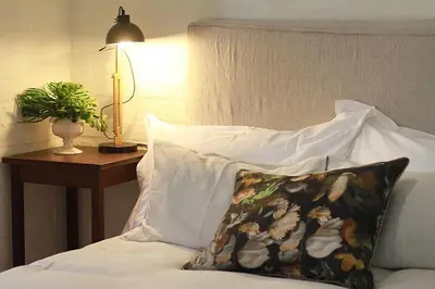 a bed with a pillow and a table with a lamp at Courtyard Studio lights and wi fi during load shedding in Stellenbosch