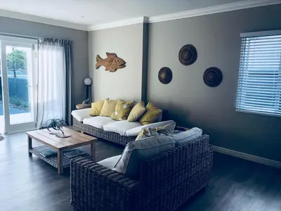 a living room with a couch and a table at Corban Cottage in Hermanus