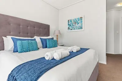 a bedroom with a large bed with towels on it at Lagoon Beach 231 in Cape Town