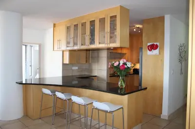a kitchen with a counter with stools and a vase of flowers at Hibernian Towers 505 in Strand