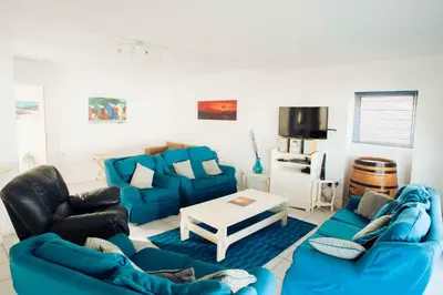 a living room with blue couches and a table at 20 Cayman Beach, Gordon's Bay in Gordonʼs Bay