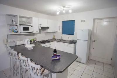 a kitchen with a counter with a bottle of wine on it at 20 Cayman Beach, Gordon's Bay in Gordonʼs Bay