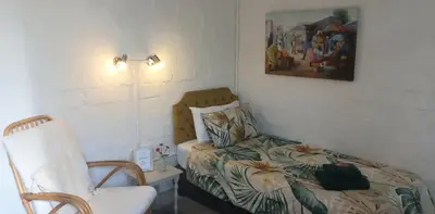 a small bedroom with a bed and a chair at 19 on Robyn in Durbanville